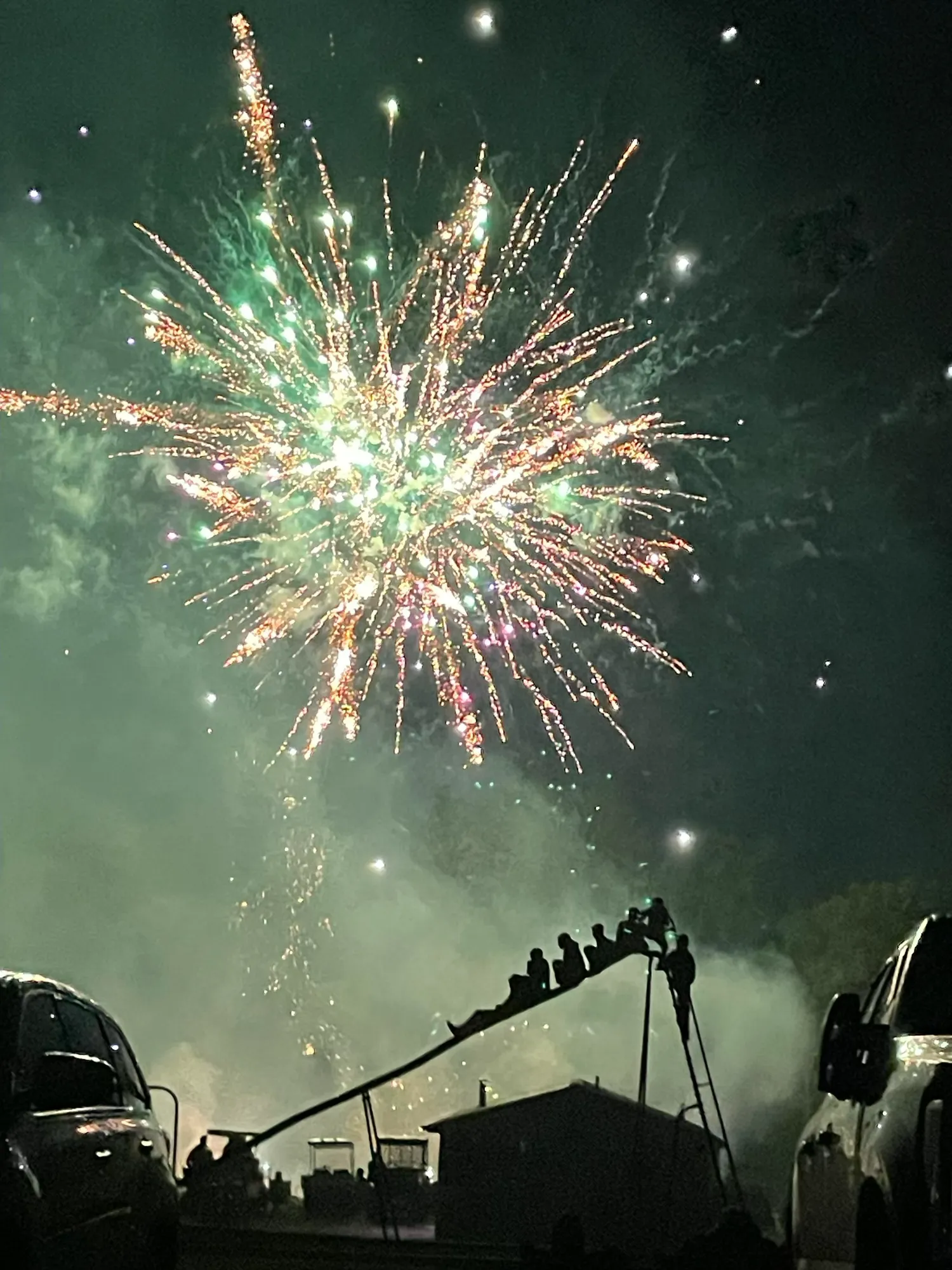 Green and gold fireworks bursting over the gathered crowd