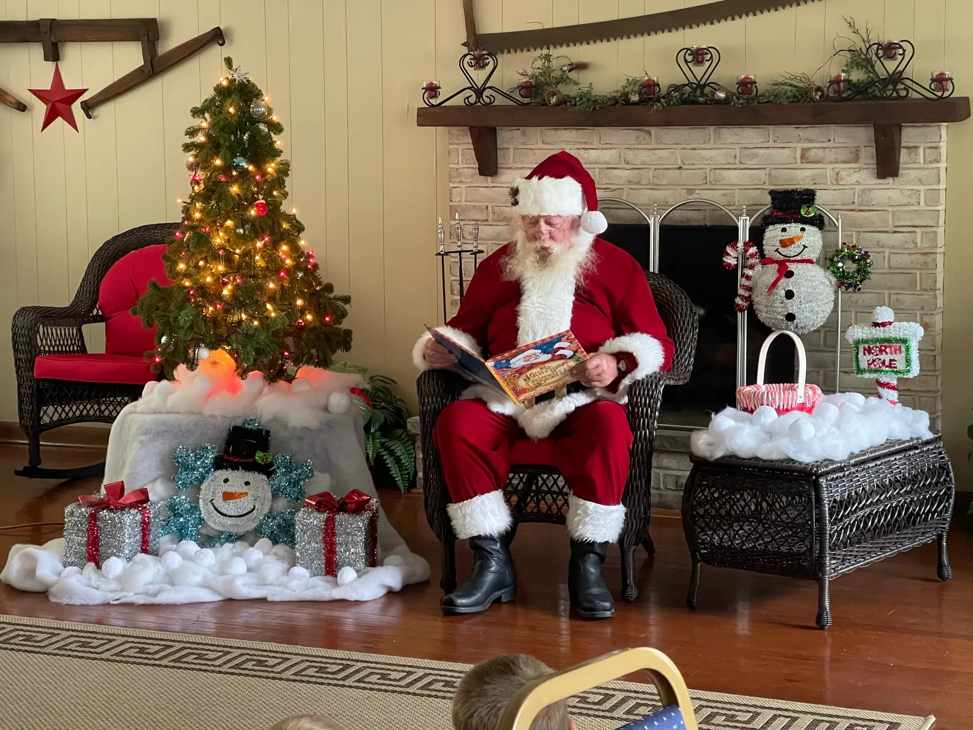 Santa reading to children by the Christmas tree during a holiday event at the lodge
